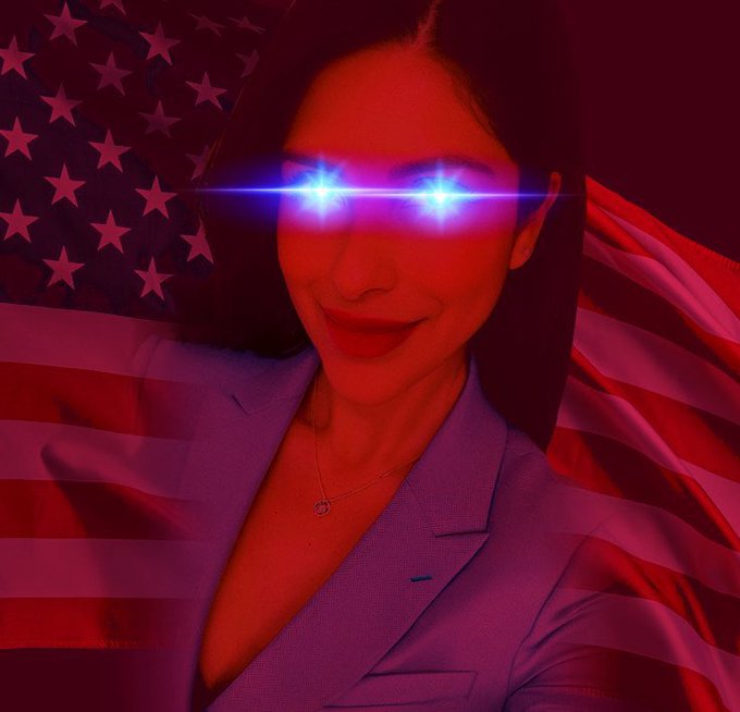 A dramatic red-tinted portrait of a smiling woman wearing a blazer with glowing blue eyes overlaid against a backdrop of the American flag.