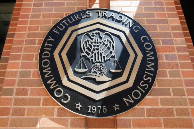 The image shows the official seal of the U.S. Commodity Futures Trading Commission (CFTC), established in 1975, mounted on a brick wall. The emblem features an eagle, scales of justice, and a gear—symbols reflecting the agency's regulatory authority, which connects to the post about the CFTC suing a Florida man for an alleged $397 million cryptocurrency Ponzi scheme.