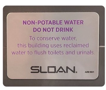A metallic plaque reading 'NON-POTABLE WATER DO NOT DRINK' stating that the building uses reclaimed water to flush toilets and urinals, branded with the 'SLOAN' logo.