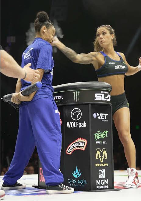 Two female MMA fighters face off in the ring at a Premier MMA League event, with a sponsored podium displaying logos for WOLFpak, Telemundo, The Beast, RAM, Dios Azul Tequila, and MGM Rewards.