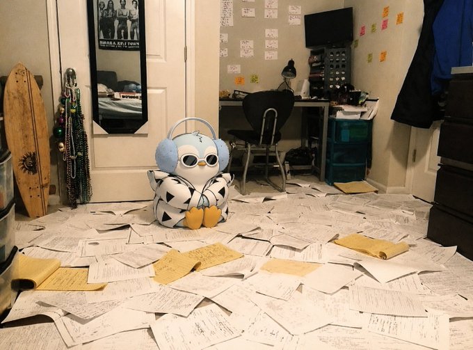 The image features a room with scattered papers, including white paper and yellow paper, covering the floor. A stuffed animal, possibly a bird or a penguin, sits amidst the mess. The room appears to be messy and disorganized, with various items such as books, a keyboard, and a TV visible in the background. The post about Bitcoin and cryptocurrency is displayed on the wall above the scattered papers, suggesting that this scene might have taken place recently or is related to the ongoing discussion around Bitcoin and its fluctuations in value.
