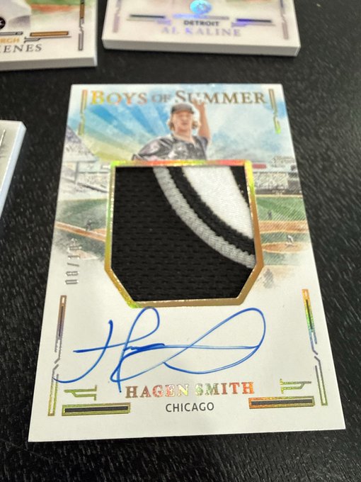 A Hagen Smith "Boys of Summer" Gold on-card patch autograph card, numbered 08/10, features a black and white fabric swatch with blue ink signature and is identified as a Chicago baseball card. The image displays the card along with other partially visible trading cards in the background.