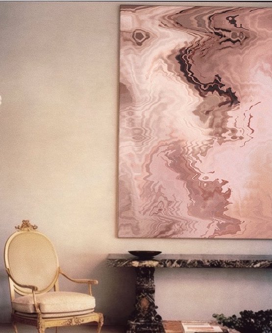 An elegant room features a classic gold and cream chair, a marble pedestal table, and a large abstract artwork in pink and brown tones.