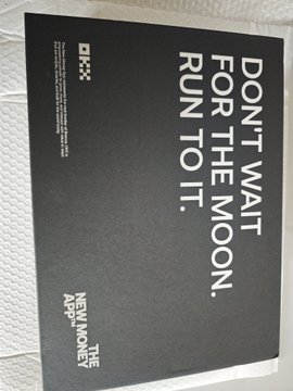 A black card or promotional item displays the text 'DON'T WAIT FOR THE MOON. RUN TO IT.' alongside a logo and 'NEW MONEY APP' text.