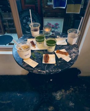 A cozy morning setup at GML coffee shop features a marble table with "GML" labeled matcha and coffee drinks alongside pastries, candles, and vintage decor, perfectly capturing the relaxed aesthetic described in the post.