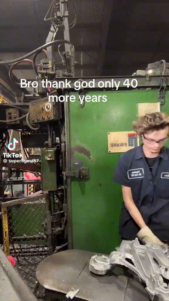The image shows a man wearing blue overalls working inside an industrial setting, possibly at a factory or workshop. The caption of the image reads "BREATHE GOD ONLY 40 YEARS MORE YEARS", which seems to be a humorous statement about the longevity of the person's job. The post also mentions that people are underestimating the impact and popularity of the "NEET" movement, referring to it as a generational phenomenon.