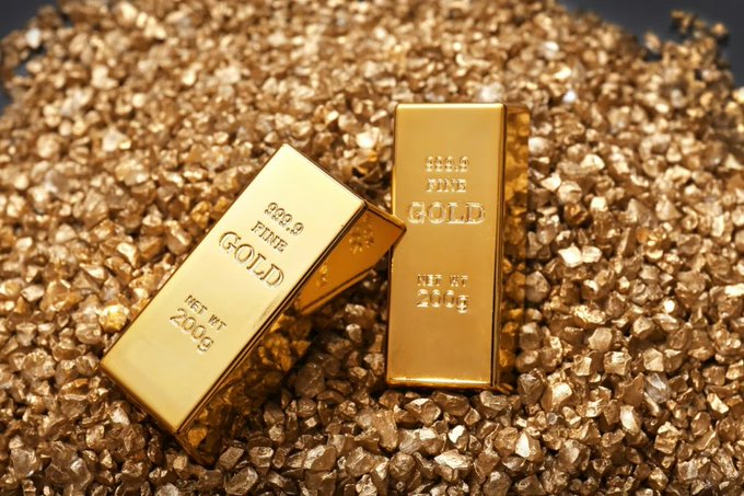 Two fine gold bars marked '999.9 FINE GOLD NET WT 200g' resting on a pile of gold nuggets against a dark background.