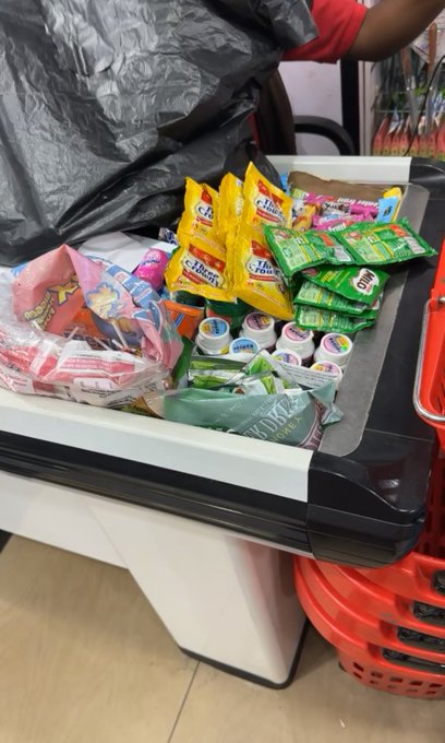 A freezer filled with assorted snacks and ice cream packages, including 'Oreo' and '7 Days' brands, at a checkout counter.