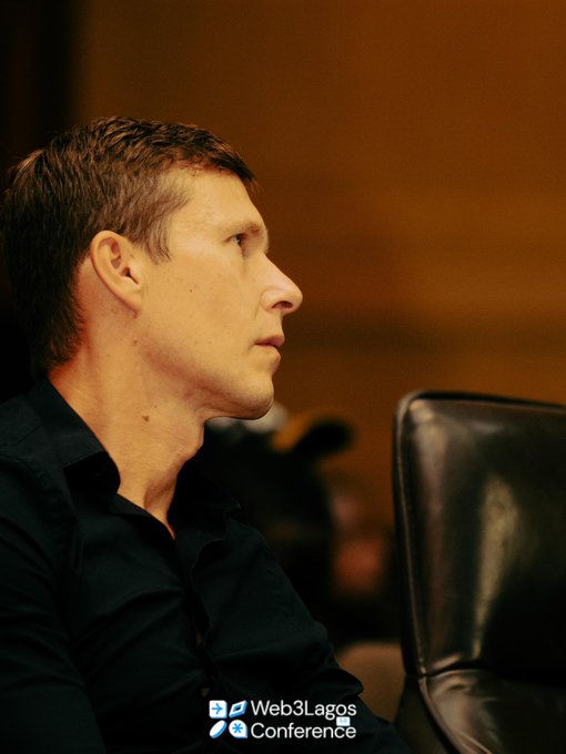 A side-profile portrait of a man in a dark shirt at the 'Web3Lagos Conference,' seated in a leather chair.