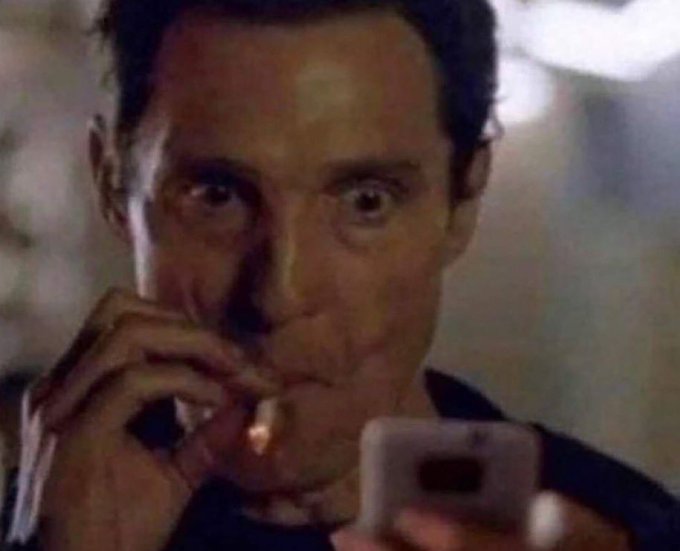 A tense-looking man stares wide-eyed at a smartphone, cigarette in hand, his anxious expression mirroring the post's depiction of a trader anxiously watching a low-cap memecoin's rapid price swings on a mobile app.
