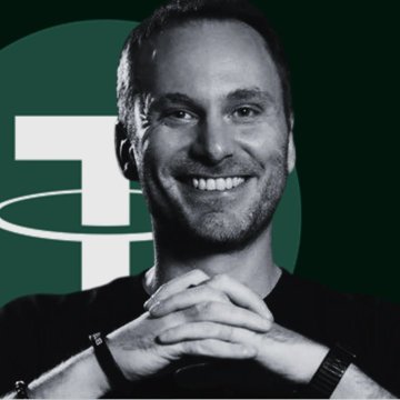 The image features a man with a big smile, wearing a black shirt, and his hands are crossed over each other. The background of the image has a green circle with white text that says "TETHER IS TURNING ROBOTS INTO CRYPTO USERS". This suggests that the man is involved in some sort of cryptocurrency project or venture related to robots. It could be inferred that he might be working on developing a system where robots can receive crypto after completing tasks, or he may be promoting the use of cryptocurrency within the context of robot-related activities.