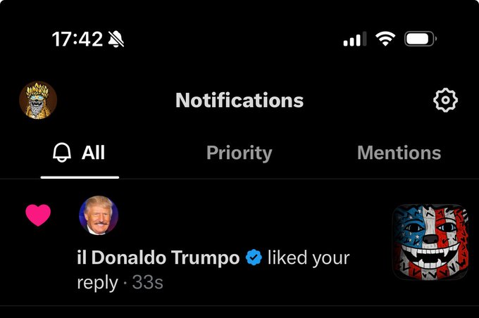 The image is a screenshot of a phone notification with various status indicators and a recent activity update. It shows the current time, network signal strength, Wi-Fi status, and battery level at the top, with 8:42 displayed. The notification from a user named "il Donald Trumpo" (verified account) highlights that they have liked a reply from the owner of the profile, which occurred 33 seconds ago, denoted by the text "reply · 33s." To the right of this notification is a graphical representation of a character, notable for its intense expression. The gray bar indicates the device is in silent mode. The original post references a bullish stance on the stock $FUZZY, suggesting the profile owner has a positive outlook on this market trend, and it likely relates to the character's enthusiastic demeanor in the graphic.