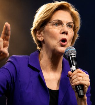 Senator Elizabeth Warren, wearing a purple blazer and glasses, speaks passionately into a microphone while gesturing with her hand, delivering her criticism of the current proposed crypto legislation.
