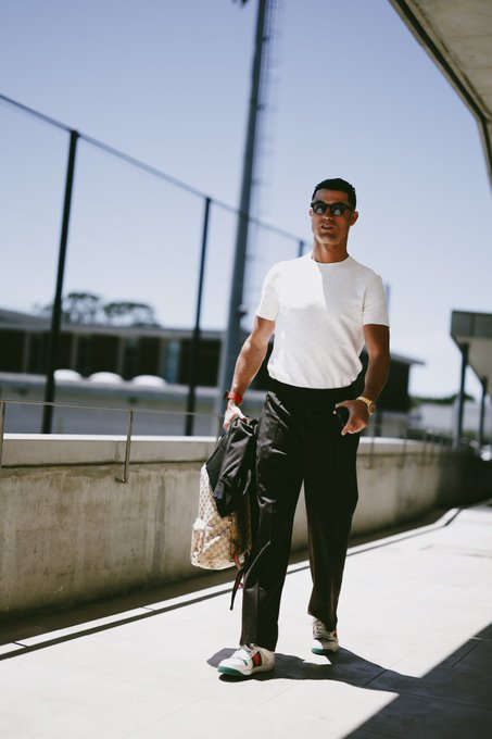 The image shows a young man walking down a sidewalk, wearing a white shirt and glasses, carrying a bag over his shoulder. There are two posts visible in the background - one near him and another further away. The post near him reads "After the change of Name from TON - GRAM". This suggests that the name he now wears is related to the payment for his services. Interestingly, six months later, there is a new post stating that 1 GRAM = $50. This implies a possible connection between the amount he charged and the number of names he changed.