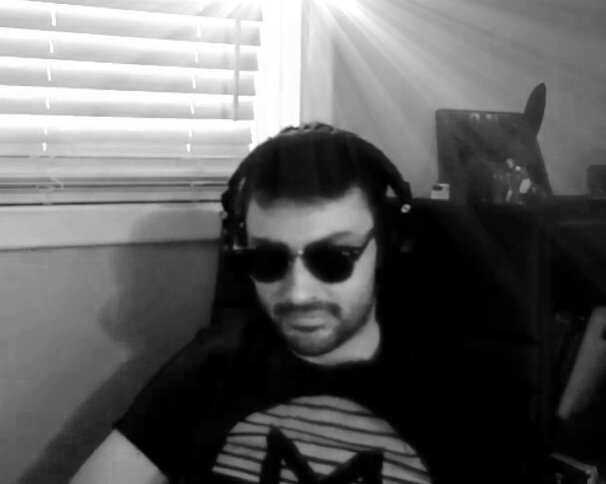 The image features a man wearing sunglasses, sitting in front of a window with blinds. The man has a serious expression as he looks at something off-camera. There are also books visible near him, suggesting that he might be working or studying from home. The photo is black and white, which adds to the overall moody atmosphere. The caption reads "Monero added 1.2 Billions in Market Cap in 3 days. AI agents are using it to wash the $ taken from exploits?". This statement seems unrelated to the main subject of the image - a man wearing sunglasses sitting by a window with blinds and looking at something off-camera.