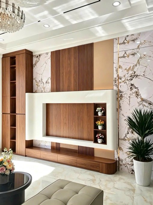 A modern living room interior featuring a large wooden TV wall unit with marble accent panels, decorative shelving, and a potted plant.