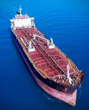 An aerial photograph of a large red and black oil tanker/cargo ship sailing on deep blue ocean waters.