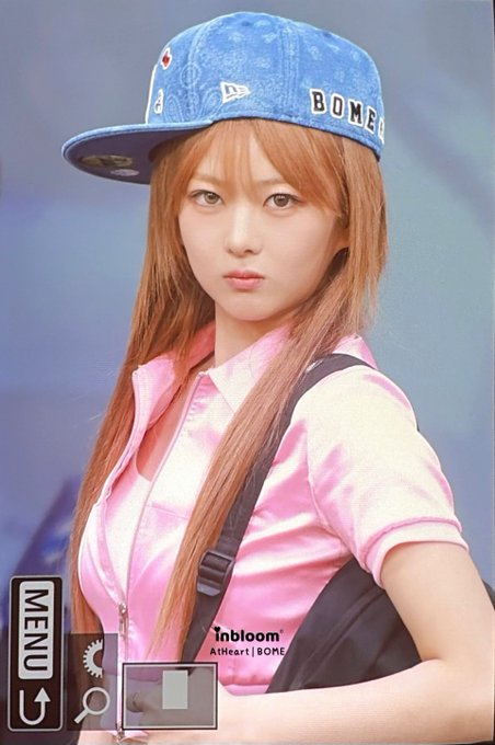 A young Japanese woman with reddish-brown hair wearing a pink satin cap-sleeve top and a blue baseball cap, with text reading 'BOME,' 'Inbloom,' 'At Heart | BOME,' and a 'MENU' button visible.