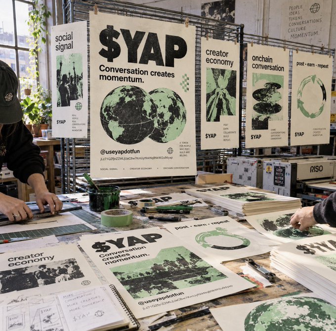 A screen-printing workshop displaying '$YAP - Conversation creates momentum' posters with handles '@useyapdotfun', alongside other designs about 'social signal', 'creator economy', and 'onchain conversation'.