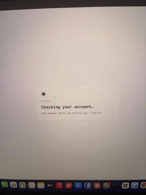 A photograph of a Mac screen showing a PayBox pop-up reading "Checking your account... One moment while we verify your sign-in," with the macOS dock visible at the bottom—capturing the frustrating sign-in glitch that prompted the user to publicly call out PayBox alongside the mention of crypto.