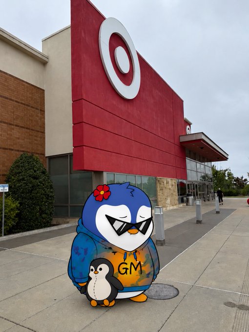 An image showing a Target store with its red facade and bullseye logo, with a cartoon penguin wearing sunglasses and a hoodie that says 'GM' edited into the foreground.