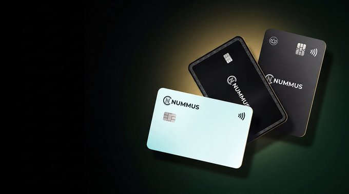 Three 'NUMMUS' branded cards—white, black, and dark gray—are displayed at angles against a dark green background with spotlit illumination.