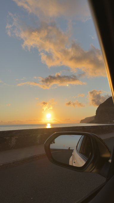 A scenic sunset captured from inside a car driving along a coastal road, with the side mirror reflecting the view and the sun setting over the ocean. The image pairs with the post's relaxed "good night" sentiment and request for a $SOL (Solana) wallet address to send crypto tips before bed.