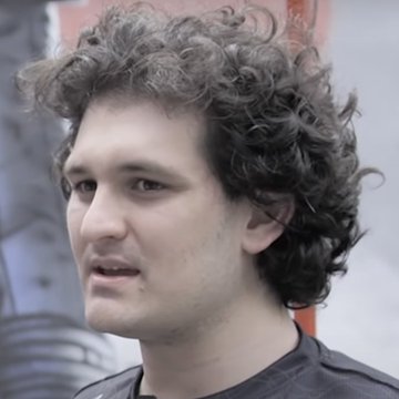 A young man with curly dark hair, identified as Uniswap founder Hayden Adams, is shown in a close-up portrait, likely taken at an industry event given the blurred background. The image accompanies a post about Sam Bankman-Fried allegedly paying seven figures for the Uniswap.com domain.