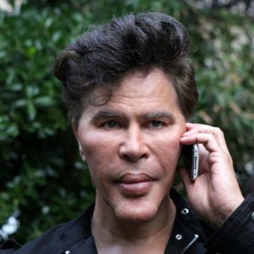 A man with wavy dark hair holds a smartphone to his ear with a serious, focused expression, set against a backdrop of green foliage. The image humorously illustrates the post's comment about someone being "locked out" for anticipating a market correction and selling too quickly.