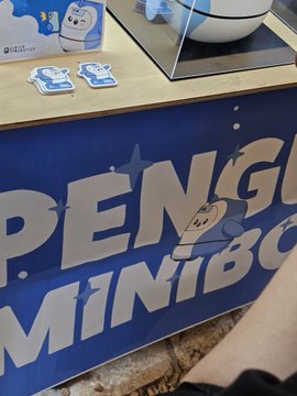 A promotional display with large blue letters spelling 'PENGU MINIBO' alongside cartoon penguin merchandise and character stands.