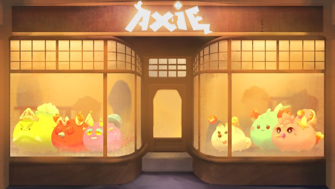 A glowing storefront labeled "AXIE" displays a colorful collection of cute Axie creatures in window displays on both sides of an open door, illustrating the variety of characters players can collect and build a team with. The whimsical, inviting scene visually reinforces the post's message about accessibility and starting your Axie journey in 2026.