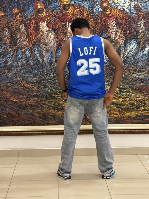 A person stands with their back to the camera wearing a blue basketball jersey with "LOFI 25" on the back, positioned in front of a large, colorful abstract painting.