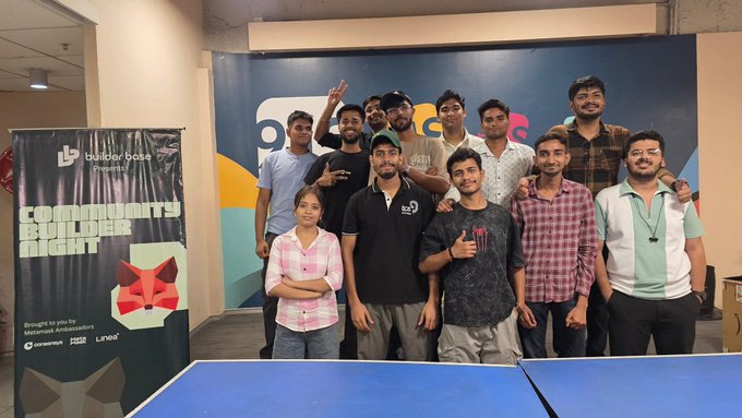 A group photo of people posing in front of a banner for 'Community Builder Night' presented by builder base, held at what appears to be a MetaMask event.