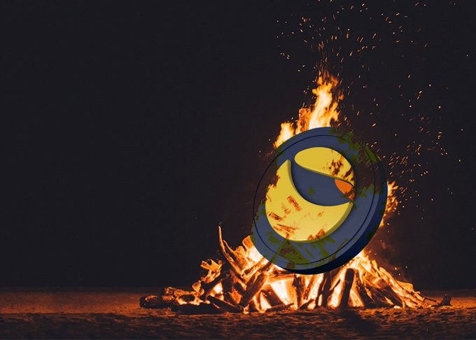 A bonfire burns brightly at night with sparks rising into the air, featuring a yellow and blue crescent moon logo overlaid in the center.