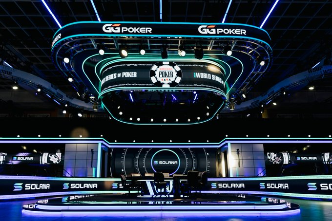 The image shows a large stage with a poker game being played at the G3 Poker event. The stage features a large screen displaying the game, surrounded by multiple chairs for players and spectators. There are also TVs mounted around the room, likely used for broadcasting the game or providing additional information to the audience. The overall atmosphere of the scene suggests that it is an exciting and engaging event where people can enjoy watching poker games unfold in real-time.