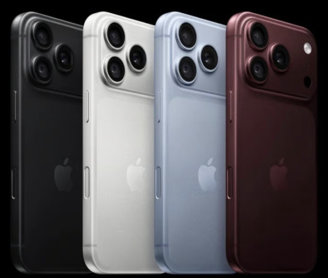 Four iPhones lined up in black, white, blue, and burgundy color variants, showing their rear triple-camera design with the 'iPhone' Apple logo.
