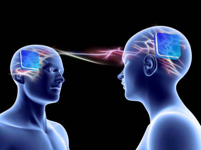 A conceptual illustration depicts two translucent blue human heads facing each other, with glowing square brain implants connected by electric energy streams between them.