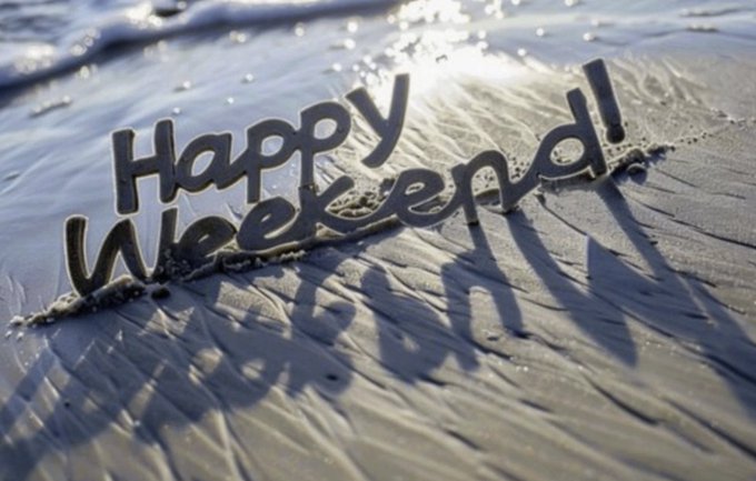 A decorative sign spells "Happy Weekend!" in metallic letters partially submerged in rippling water, reflecting sunlight.