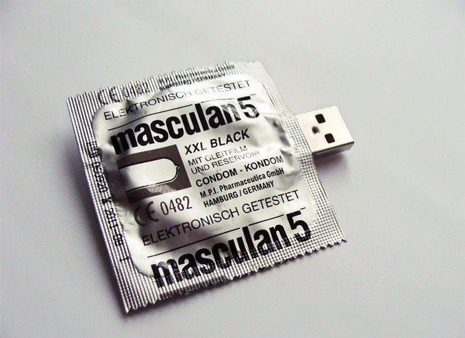A silver foil condom wrapper labeled 'masculan 5 XXL BLACK' rests next to a matching white USB flash drive shaped like the product packaging, with German text and 'M.P.I. Pharmaceutica GmbH HAMBURG/GERMANY' visible.