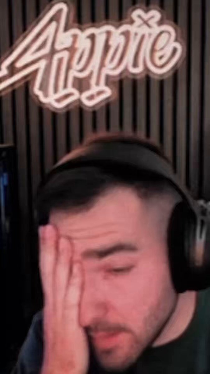 The image shows a man wearing headphones, with his hand resting over his face as if he's deep in thought or concentration. The background features a neon sign that reads "Appie" along with some text.