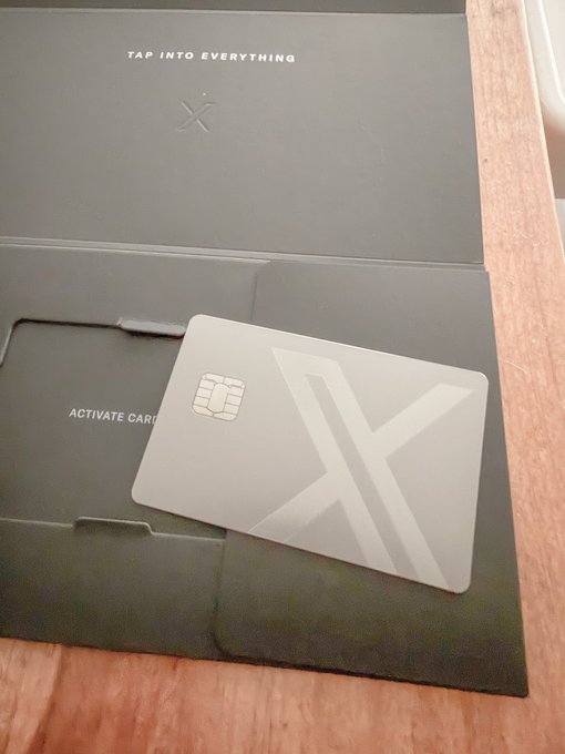 A sleek metallic X-branded debit card with an embossed chip rests on its packaging, which reads 'TAP INTO EVERYTHING' and 'ACTIVATE CARD'.
