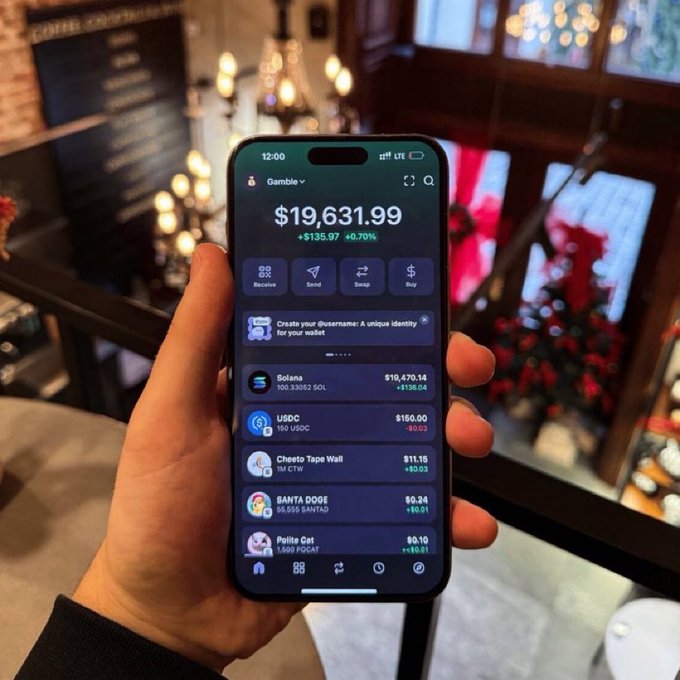 A hand holds an iPhone displaying a crypto wallet app (Phantom) with a balance of $19,631.99 (+$135.97, +0.70%), showing tokens like Solana, USDC, Cheeto Tape Wall, SANTA DOGE, and Polite Cat.