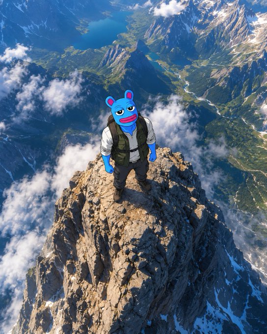 A blue cartoon bear character wearing a vest and backpack standing atop a rocky mountain peak with clouds and valleys below.