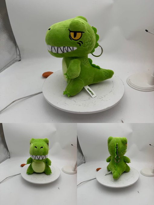Three product photos show a small green plush dinosaur toy with a wide toothy grin, yellow eyes, and scaly textured details, displayed from multiple angles on a white rotating display stand.