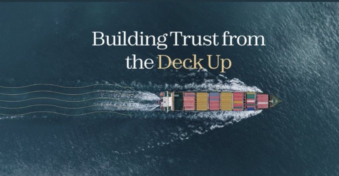 An aerial view of a large container ship sailing on the ocean with the text overlay 'Building Trust from the Deck Up'.