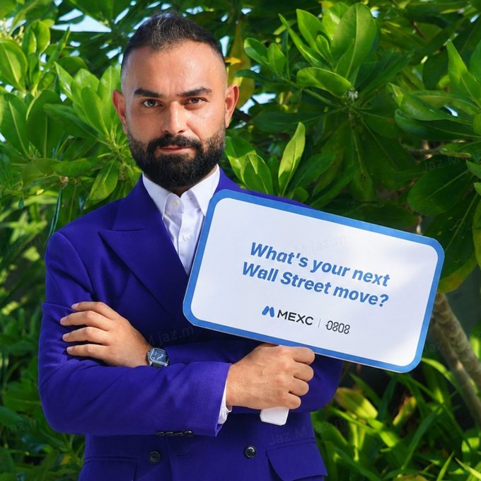 A bearded man in a vibrant purple suit stands confidently in front of lush greenery, holding a sign that reads "What's your next Wall Street move?" featuring the MEXC | 0808 branding, visually prompting the caption's question about investment decisions ahead of NVIDIA's earnings report.