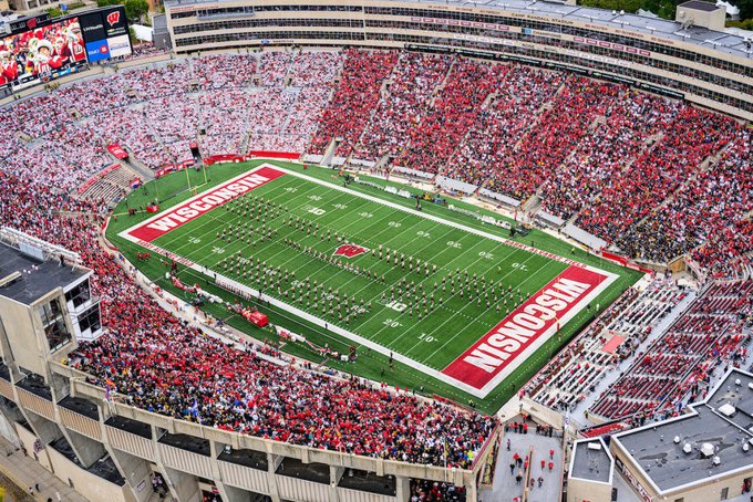 An aerial view of a packed Camp Randall Stadium featuring a football field with 'WISCONSIN' painted in the red end zones.