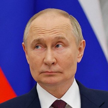 A man in a dark suit and red tie stands in front of a blurred Russian flag, looking off to the side, in an image accompanying a post about Russia's landmark Bitcoin and crypto market structure law taking effect on September 1, 2026.
