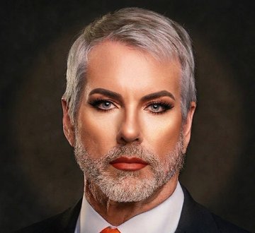The image features a man with blonde hair, dressed in formal attire - a suit, tie, and black pants. The man has an unconventional look due to his beard and mustache, which contrasts with his formal outfit. This photo appears to be taken at Pride Month, as indicated by the accompanying text that states "BREAKING: Michael Saylor'S 'Strategy' sold 32 Bitcoin worth $2.5 million on the first day of Pride Month." The post seems to be an advertisement or promotion related to the event and its associated products.