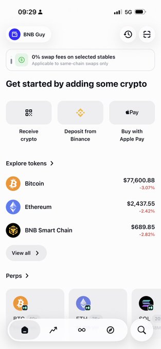A screenshot of the Trust Wallet mobile app's home screen showing a "BNB Buy" interface with a banner promoting "0% swap fees on selected stables," token prices (Bitcoin at $77,600.88, Ethereum at $2,437.55, BNB Smart Chain at $689.85), and options to receive crypto, deposit from Binance, or buy with Apple Pay—visually supporting the post's praise of Trust Wallet's clean UI and zero-fee transaction features.